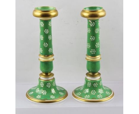 A PAIR OF LATE VICTORIAN CERAMIC CANDLESTICKS, having floral design on an apple green ground with gilded bands, 21cm high 