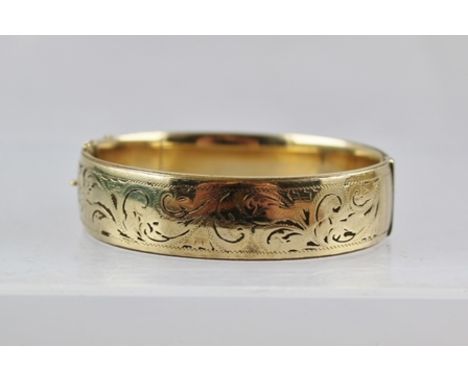 A 9CT GOLD METAL CORE BANGLE, with scroll decoration and snap clasp 