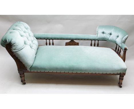 AN EDWARDIAN BEECH FRAMED CHAISE LONGUE having carved and spindle decoration, button back design with supports to either end,