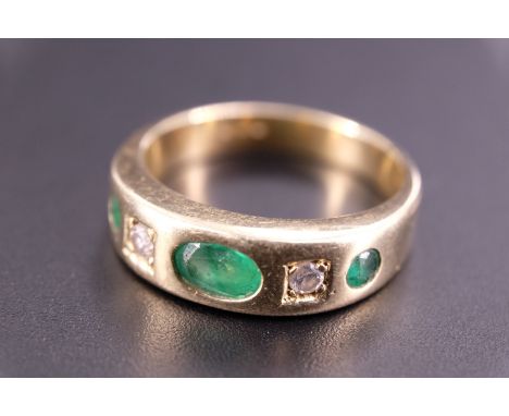 A contemporary emerald and diamond ring, comprising an oval emerald of approx 0.5 ct, and two smaller round-cut stones divide