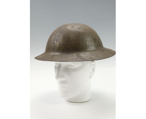A Great War British army Brodie pattern helmet, a raw-edged variant retaining its original paint and a partially obliterated 