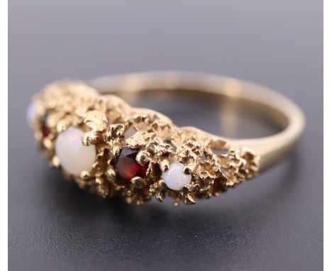 An opal and garnet ring, comprising three graded round oval cabochons divided by facet-cut garnets claw set on a densely text