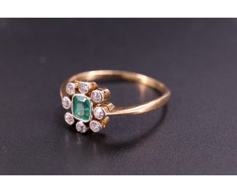 An early 20th Century emerald and diamond finger ring, comprising a central cushion-cut stone platinum millegrain set within 