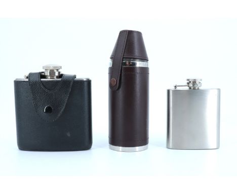 A stainless steel flask and toddy cup set together with two similar hip flasks, tallest 15 cm