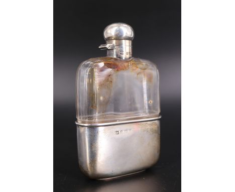 An Edwardian silver-mounted cut glass hip flask, having an oblate hinged cap closing by means of a bayonet catch, the base se