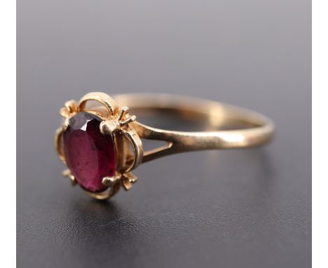 A vintage almandine and 9 ct gold ring, the oval cut stone of approx 1 ct claw set within a quatrefoil frame between the bifu