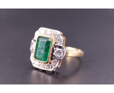 An Art Deco emerald and diamond ring, the central 'emerald' cut 1.75 carat emerald set in a yellow metal bezel, terraced abov