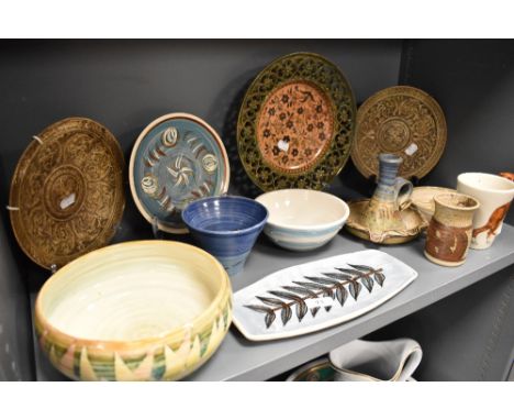 A shelf of studio pottery including bowls, dishes, plates and a brutalist style chamber stick.