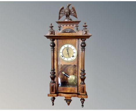 A walnut eight day wall clock with brass and enamel dial, surmounted by an eagle.