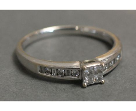 An 18ct. White Gold Diamond Ring with four claw set diamonds and with diamond shoulders