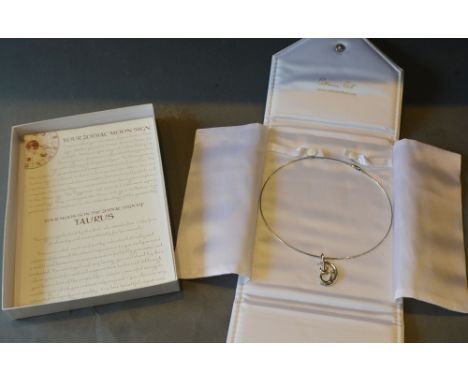 A 9ct. White Gold Taurus Moon Sign Pendant set with a Diamond, 7 gms. with an 18ct. white gold chain, 11 gms. all retailed by