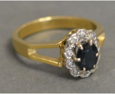 An 18ct. Yellow Gold Diamond and Sapphire Cluster Ring, set with a central oval sapphire surrounded by diamonds within a pier