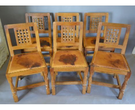 A Set of Six Robert (Mouseman) Thompson Light Oak Dining Chairs, with lattice pierced backs above the original leather brass 