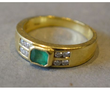 An 18ct. Yellow Gold Emerald and Diamond Ring set with central emerald flanked by eight diamonds