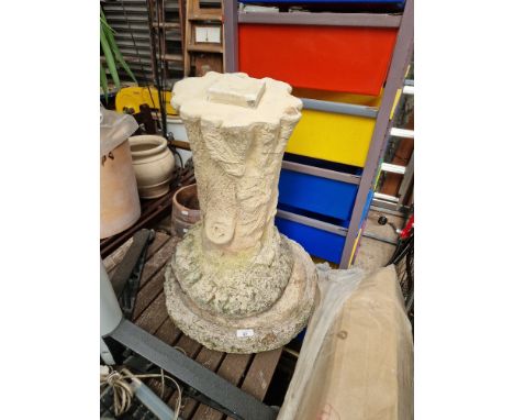A concrete garden birdbath on a tree trunk style plinth  