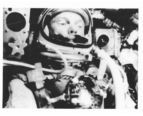 A portrait of John Glenn, the first American to orbit the Earth, glancing out of porthole as he re-entered the atmosphere, ta