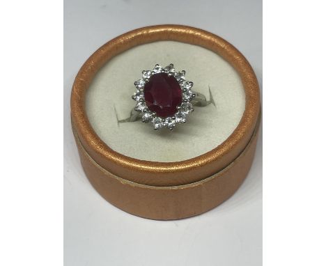 A MARKED 925 SILVER RING WITH CENTRE RUBY COLOURED STONE SURROUNDED BY CLEAR SONES SIZE R IN A PRESENTATION BOX 