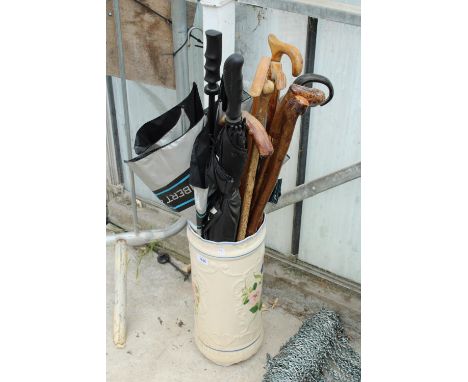 A CERAMIC STICK STAND WITH AN ASSORTMENT OF WALKING STICKS AND UMBRELLAS ETC 