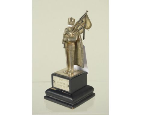 A silver figure of a pipe playing Gurkha on wooden plinth, plaque reads 'The Gurkha Engineers' and 'Lt Col LH Mutton Re 1967-