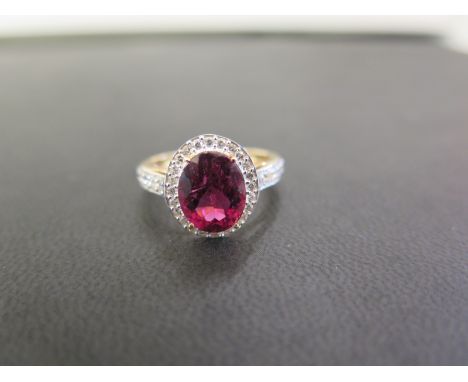 An 18ct gold tourmaline and brilliant-cut diamond cluster ring - With similarly-cut diamond shoulders and plain half-band - H