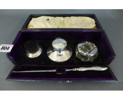 An Edwardian silver cased desk set comprising capstan inkwell with glass insert, brush, sealer and letter opener - Birmingham