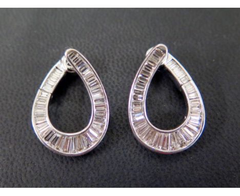 A pair of diamond earrings - Of hoop design the graduated baguette-cut diamonds within a channel setting to the hinged clasp 