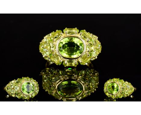 Peridot East/West Cluster Ring, to the centre a bezel set oval cut peridot of a generous 2.75cts, surrounded by a further 5.5