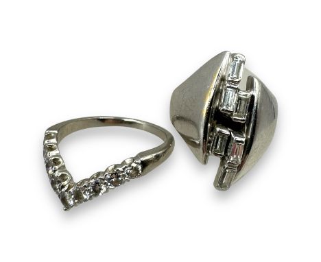 Two diamond set white precious metal dress rings. The first is a modernist off-marquise shaped ring, stamped 14k and tests as