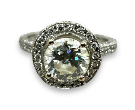 A diamond solitaire halo ring, featuring pave set shoulders, with a central round brilliant cut stone of an estimated 1.4 car