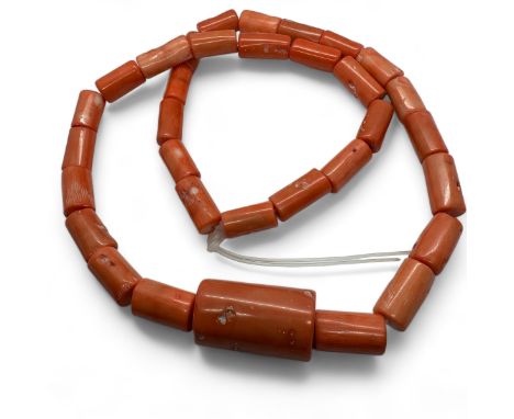 A large strand of unused polished coral barrel beads, together with a vintage jadeite carved and a contemporary "mutton fat" 