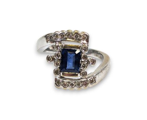 A handmade 18ct white gold sapphire and diamond dress ring. Featuring a central emerald cut sapphire measuring approximately 