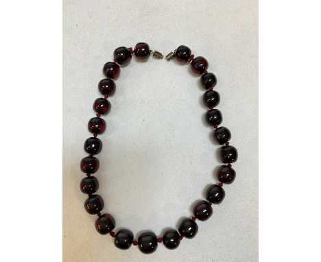 A vintage hand tied dark cherry amber bead necklace, length 38cm, each bead approx 15 x 13mm, approx 44.5g.