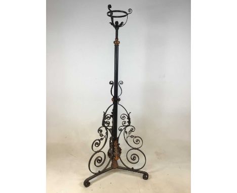 A wrought iron adjustable standard lamp with elaborate scroll detail to the tripartite base. 