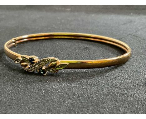 A 9ct yellow gold adjustable bangle set with floral motif centred with twin sapphires, approx. 8g.
