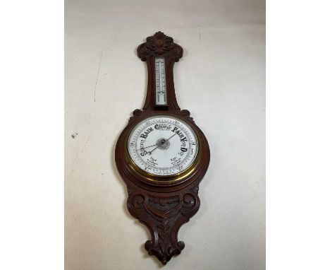 An Edwardian carved oak and aneroid wheel barometer.