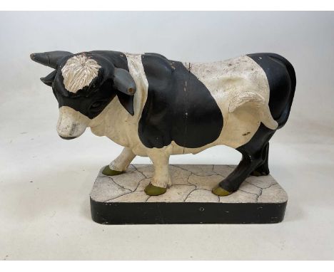 A large painted model of a cow on wooden base (af), length 55cm.Condition Report: The cow is in an as found condition. See im