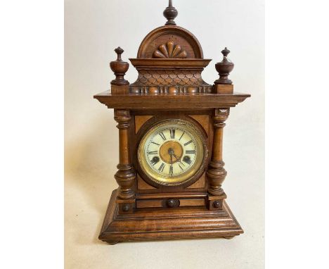 A circa 1900 German stained beech fourteen day mantel clock with Roman numerals to the circular chaptering, flanked by pilast