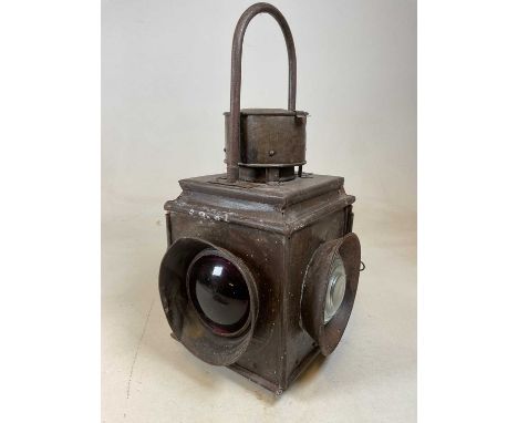 A large vintage railway lamp with four lenses and fixed loop handle.