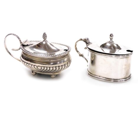 A George V silver mustard pot, of plain oval form with acorn finial and raised line decoration to rim and base, with blue gla