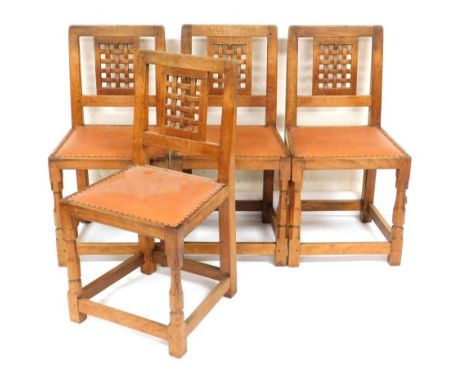 A set of four Robert Thompson Mouseman oak dining chairs, with a lattice back and leather studded seat, on block supports uni