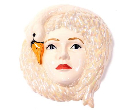 A late 20thC lustre pottery face mask, the female face enveloped by a swan, monogrammed R G and dated 99, 33cm high.