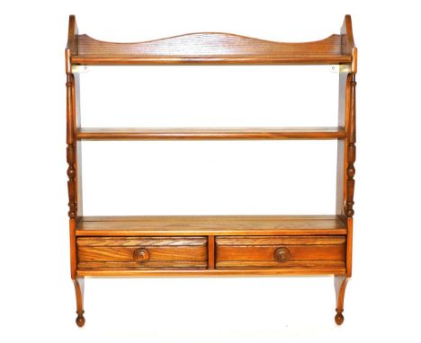 An Ercol elm wall hanging plate rack, the three shelves over a pair of frieze drawers, design 1102, 81.5cm high, 69cm wide,19