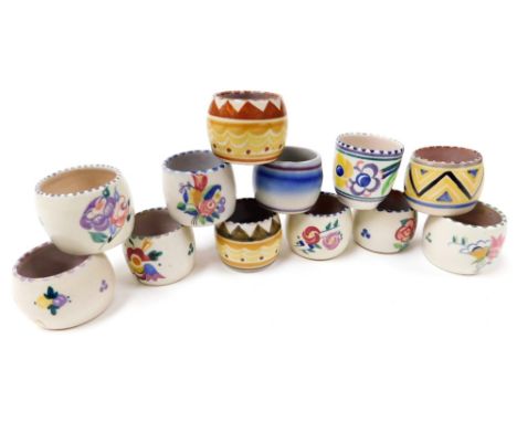 Twelve Poole pottery egg cups, traditionally painted with flowers, or with geometric banding, impressed marks. 