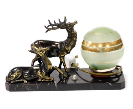 An Art Deco desk lamp, formed as a stag and deer beside an opaque frosted and gilt highlighted green glass orb, on a black ma