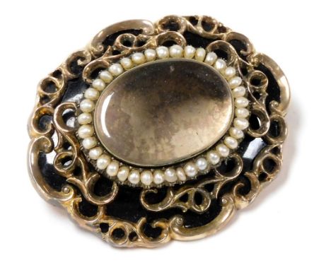 A Victorian hair locket mourning brooch, of oval form, with black enamel and yellow metal, the glass fascia border by seed pe