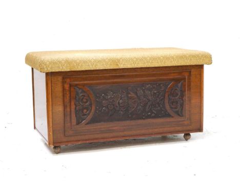 TEAK BLANKET BOXwith a lift up stuffover lid above a carved front panel, standing on later castors, 99cm wide 