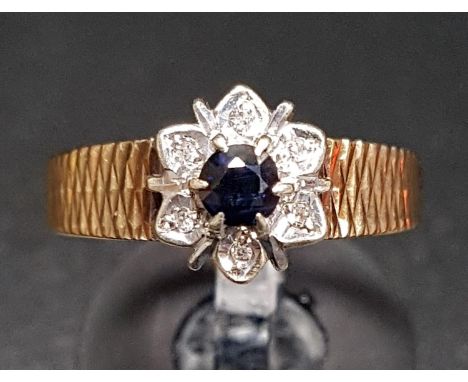 SAPPHIRE AND DIAMOND FLOWER HEAD DESIGN CLUSTER RINGthe round cut sapphire in surround of six illusion set diamonds, on nine 