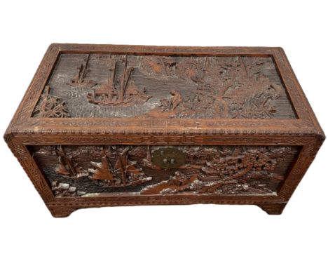 A Chinese camphor wood chest with deep relief carving and slide shelf to interior, 56 x 104 x 51.