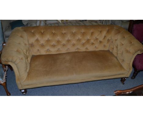 An Edwardian button back Chesterfield type sofa on turned and fluted supports