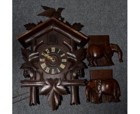 A cased cuckoo clock, with weights and pendulum; together with a pair of carved elephant bookends (3)